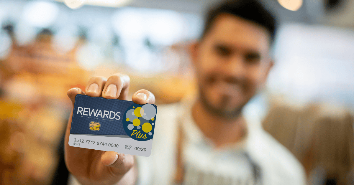 Salesman at a grocery store holding a loyalty program card up front