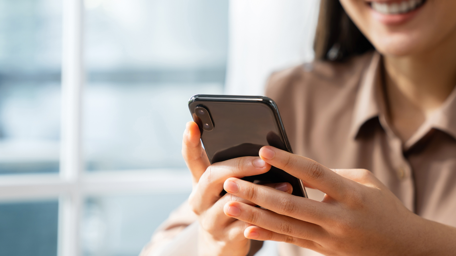 Smiling young woman hand holding smartphone with using social media on internet.