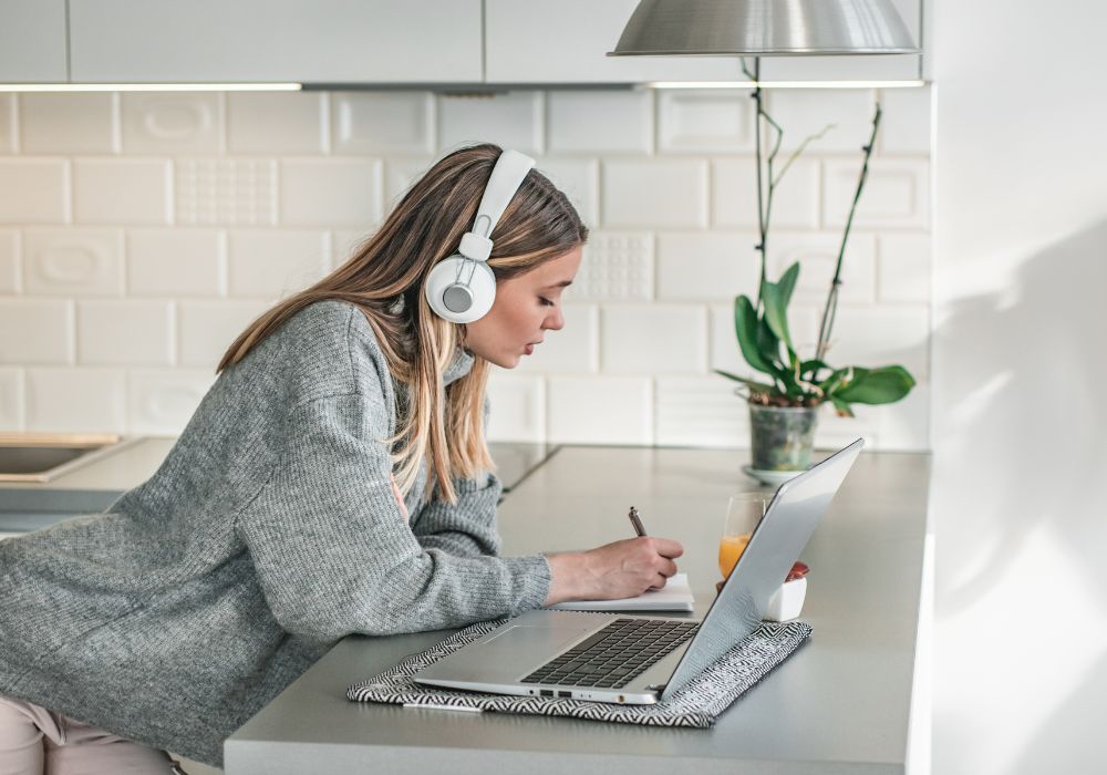 micro products; A person wearing headphones works on their laptop in the kitchen