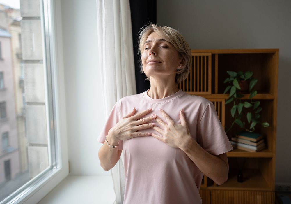 cortisol cycle: A person with their eyes closed places their hands on their chest, appearing to take a deep breath.