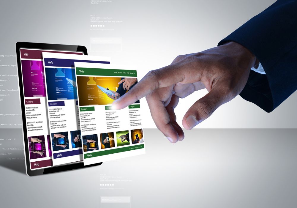 landing pages: A hand in a dark suit jacket reaches out to interact with a tablet displaying multiple web pages, with one page highlighted by a finger touch.